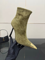 Ladies’ olive suede ankle boot on a hand, featuring pointed gold-tone toe and slim heel