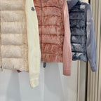 Close-up of long puffer fronts in cream, blush pink, and dark blue with knit cuffs.