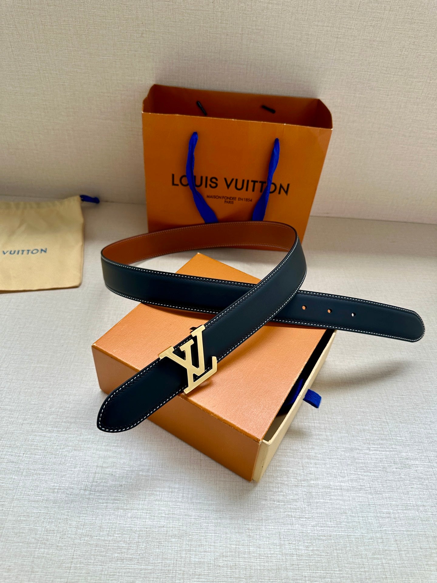Navy leather belt with gold LV buckle and overlapping strap ends