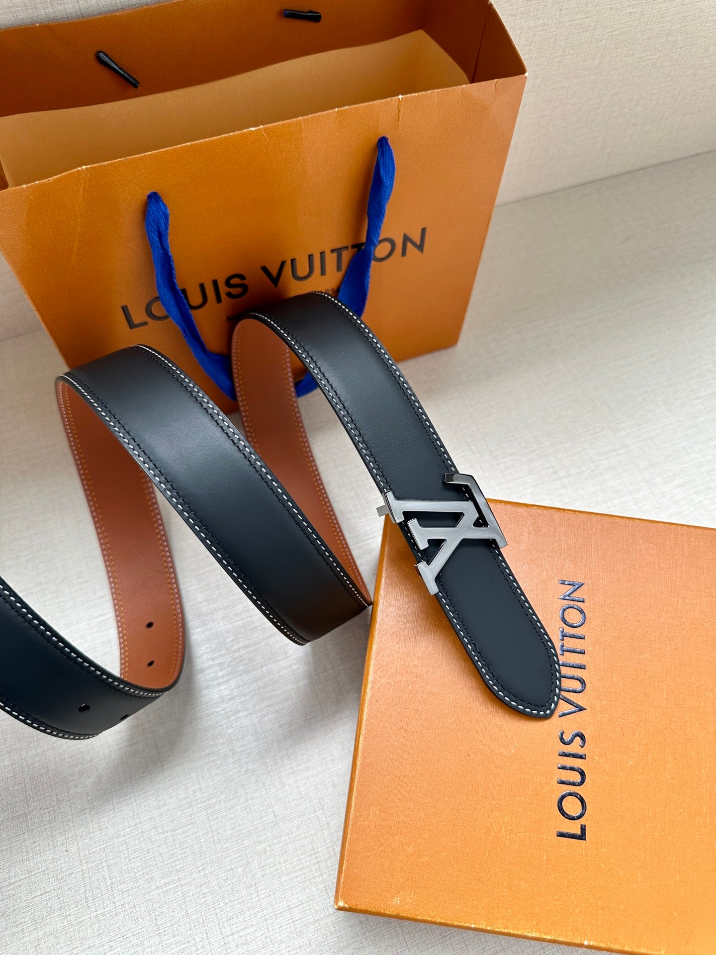 Navy leather belt with gold LV buckle, shown with orange and brown lining