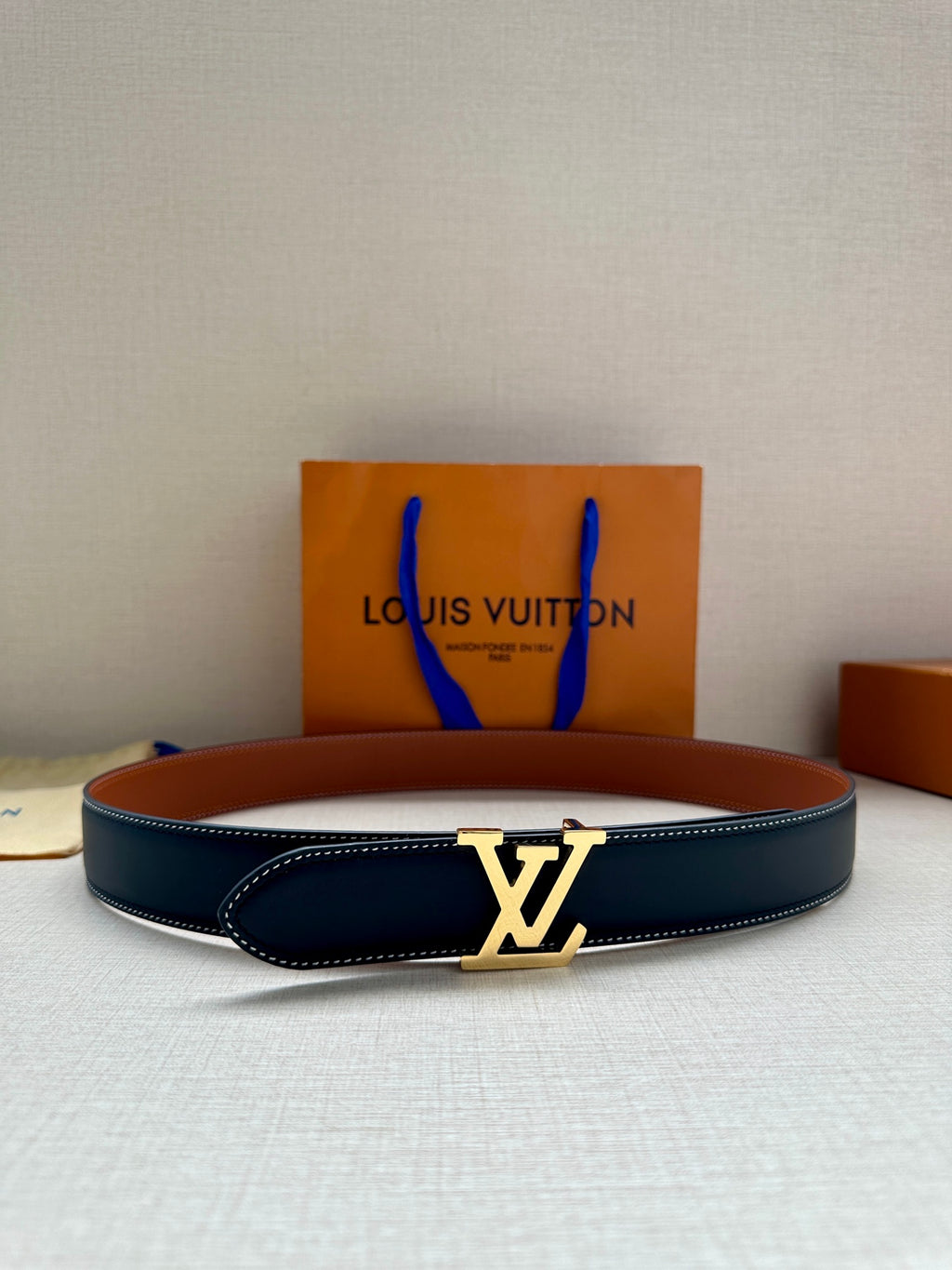 Navy leather belt with gold LV buckle, centered on the strap