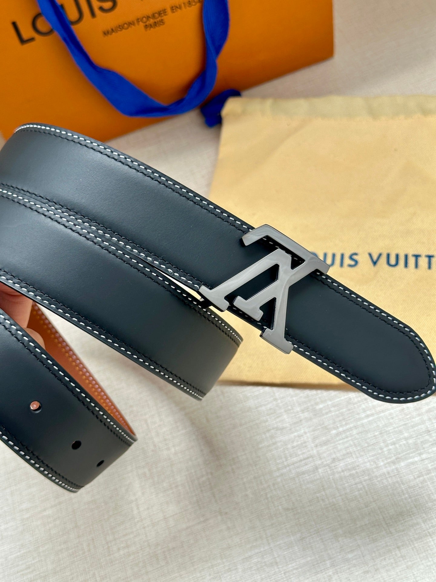 Navy leather belt with gold LV buckle, horizontal strap close-up