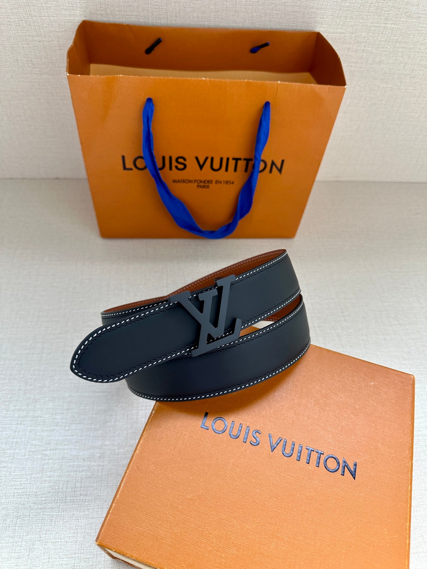 Louis Vuitton dark blue leather belt with LV buckle and tan interior edge