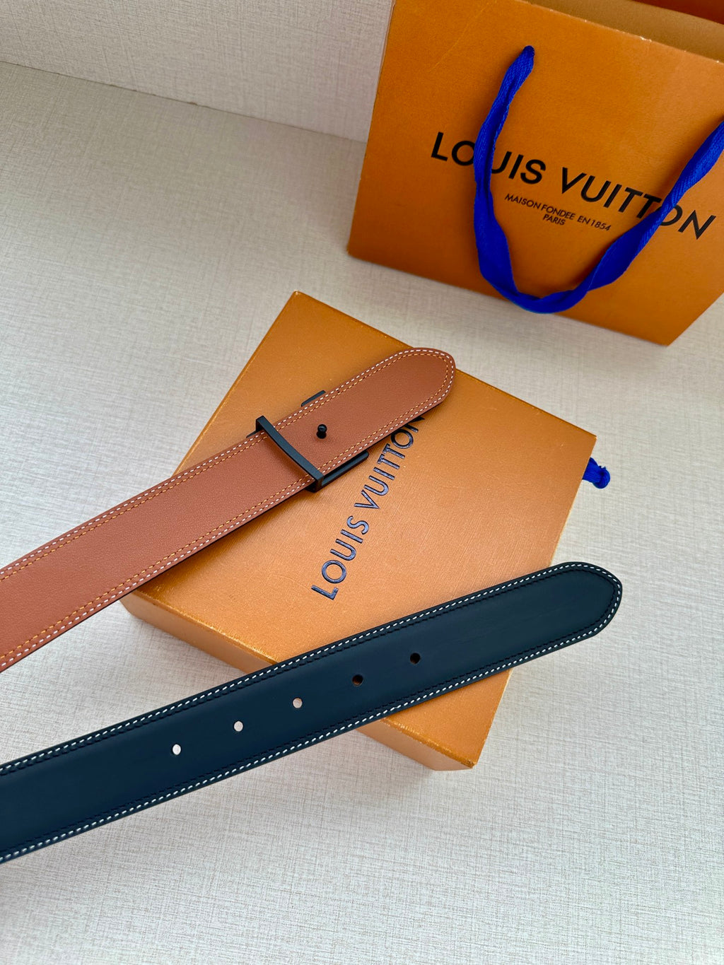 Louis Vuitton leather belt with dark blue top, tan underside, and LV buckle