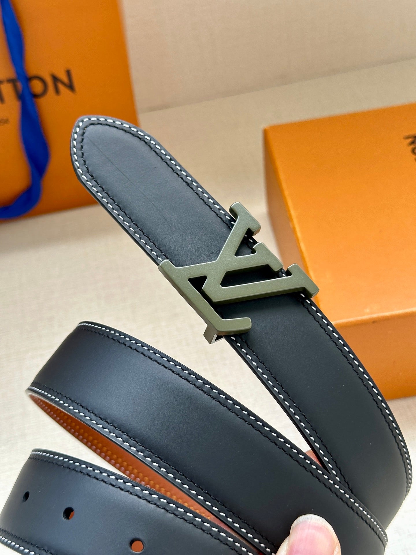 Louis Vuitton leather belt buckle detail on dark blue strap with contrast stitching