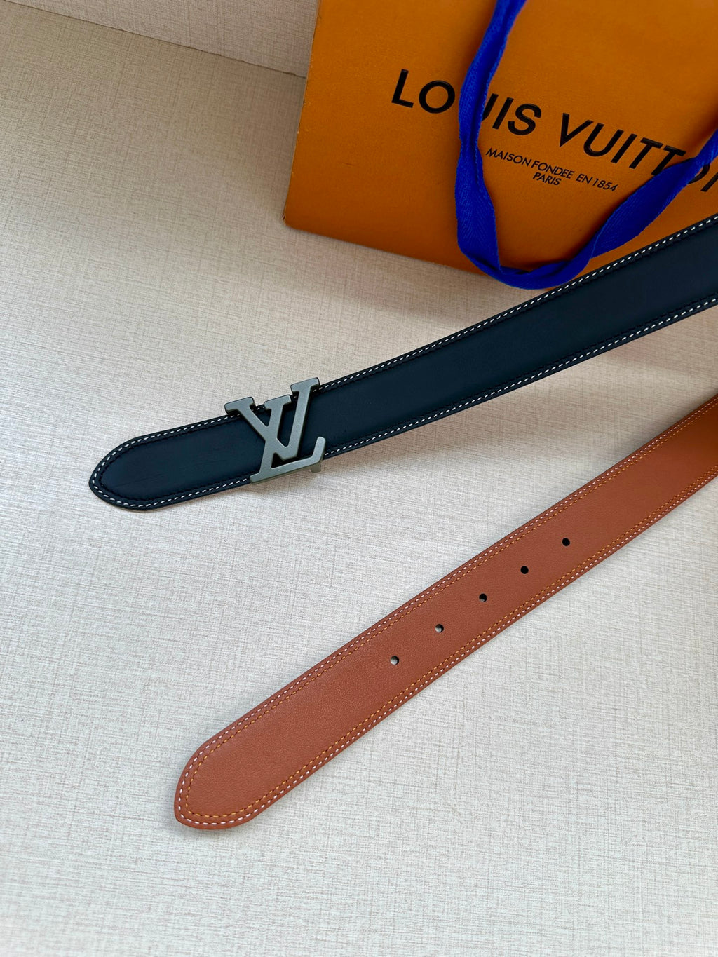 Louis Vuitton belt angle view: dark blue strap with LV buckle and perforated holes