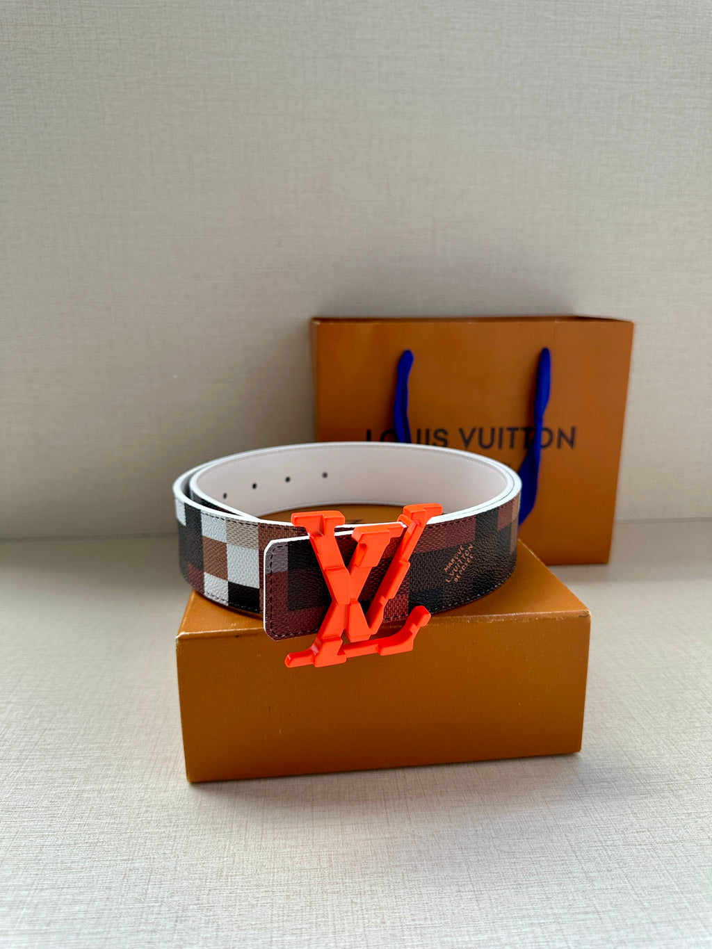 Louis Vuitton belt with white leather lining, dark checkered strap, orange LV buckle
