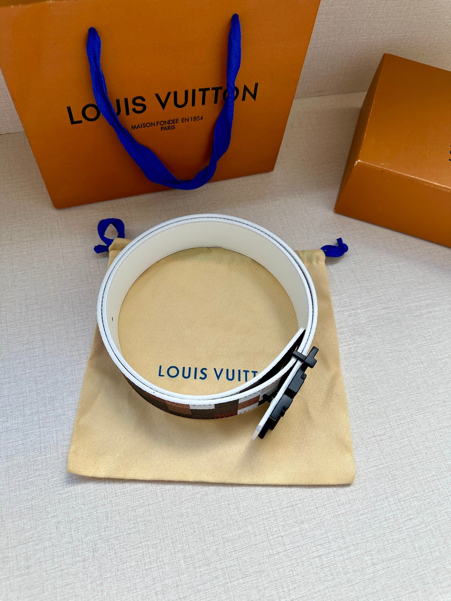 Louis Vuitton belt with white leather reverse, inner branding, and check strap edge.