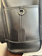 Coah leather backpack bag close-up with hanging keychain and front pocket tag