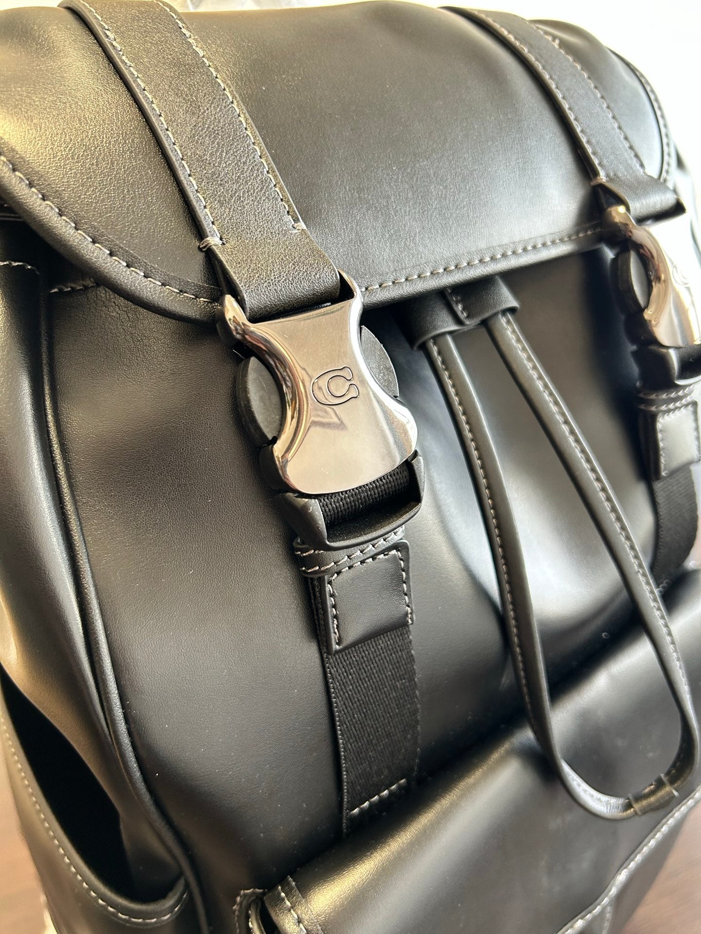Coah leather backpack bag close-up with stitched straps and metal clasp hardware