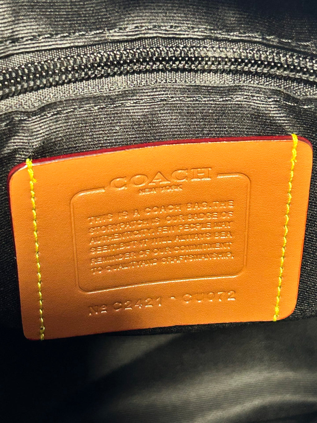 Coah leather backpack bag close-up of orange brand label on inner lining