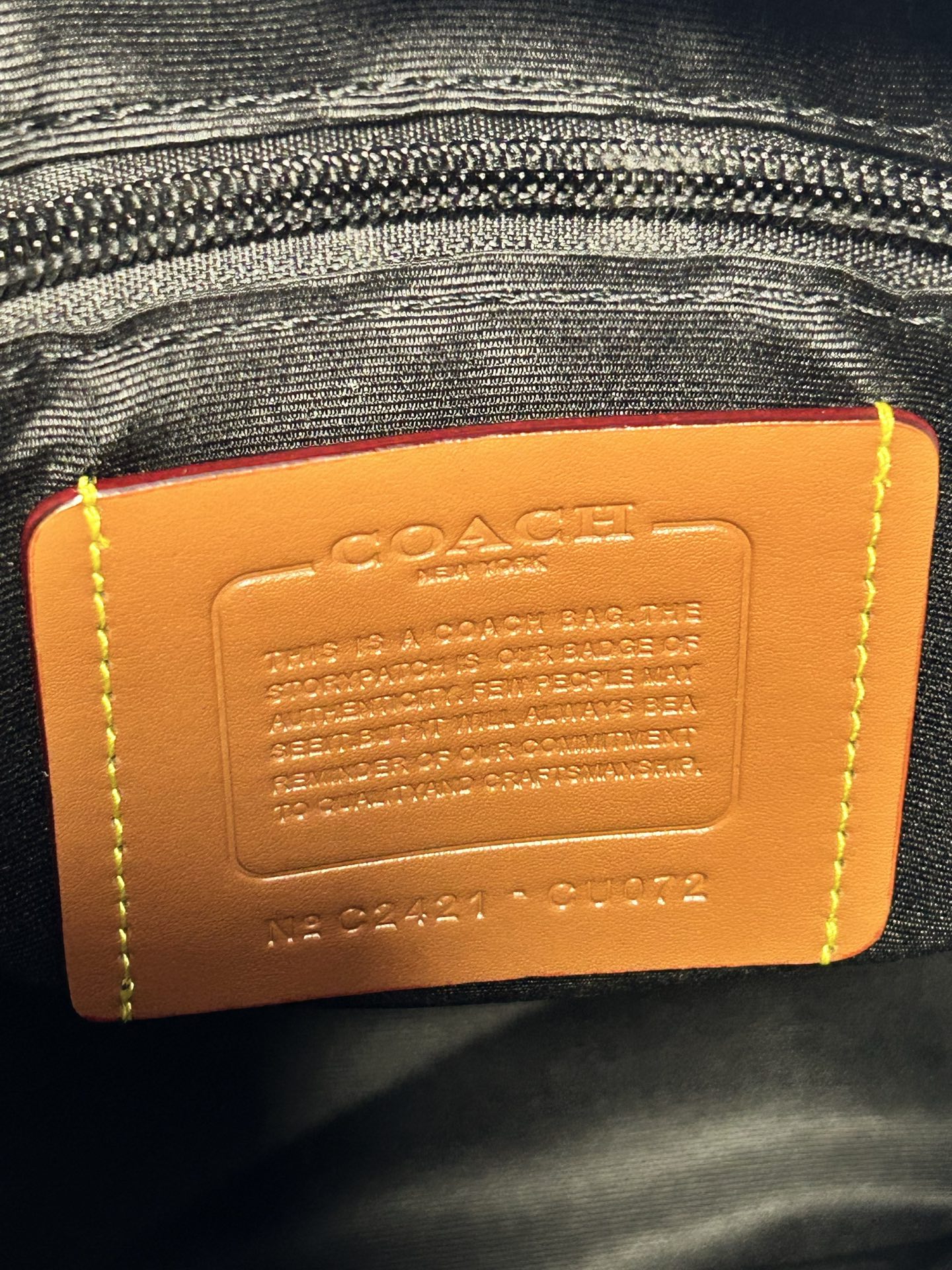 Coah leather backpack bag close-up of orange brand label on inner lining