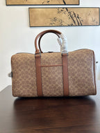 Coah duffel bag front view with monogram canvas, brown leather straps, top handles