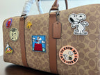 Coah duffel bag close-up, monogram canvas with patch badges and brown leather strap