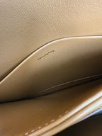 Tan leather bag interior with embossed text "TRIOMPHE" near the seam line.