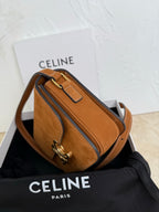 Tan suede bag with crossbody strap, front flap, and gold-tone hardware; side angle.
