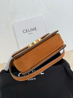 Tan suede bag with flap closure and gold-tone hardware; shown at angle with strap.