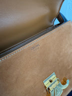 Tan leather bag with inner brand stamp on the edge seam and gold-tone emblem hardware.