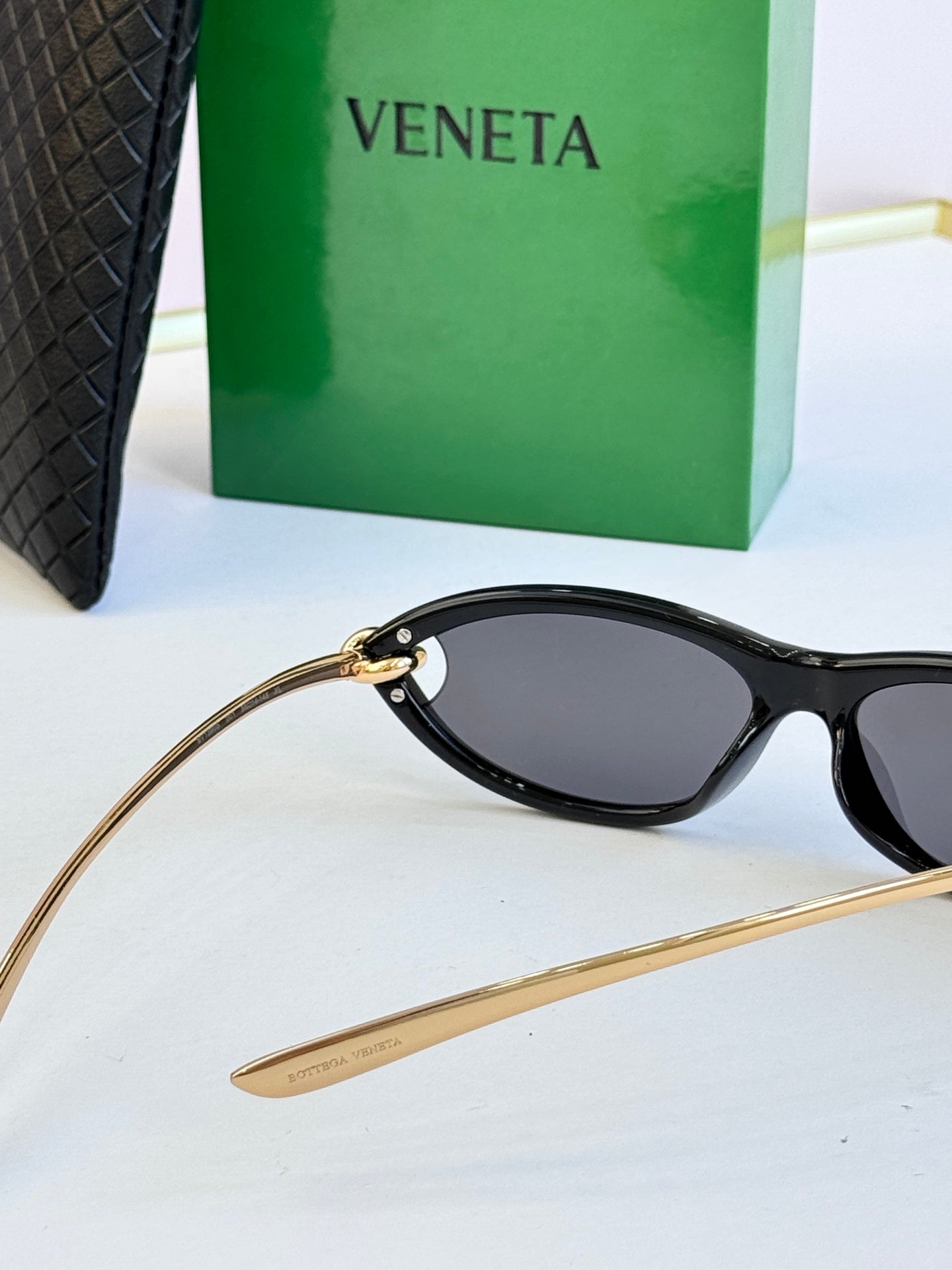 Bottega Veneta black cat-eye glasses close-up with dark lenses and gold-tone arm