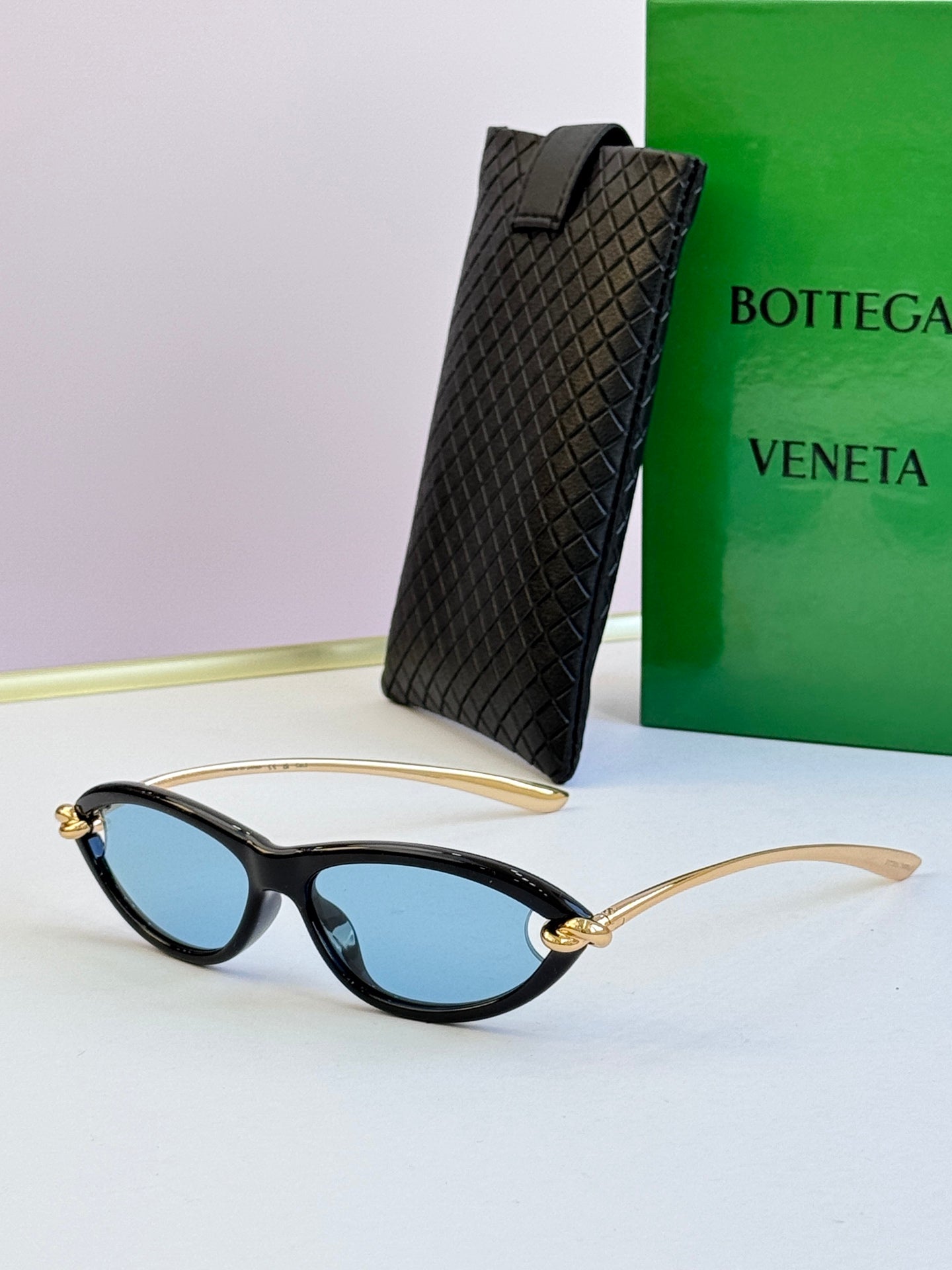 Bottega Veneta black cat-eye glasses with blue-tinted lenses and gold-tone temples