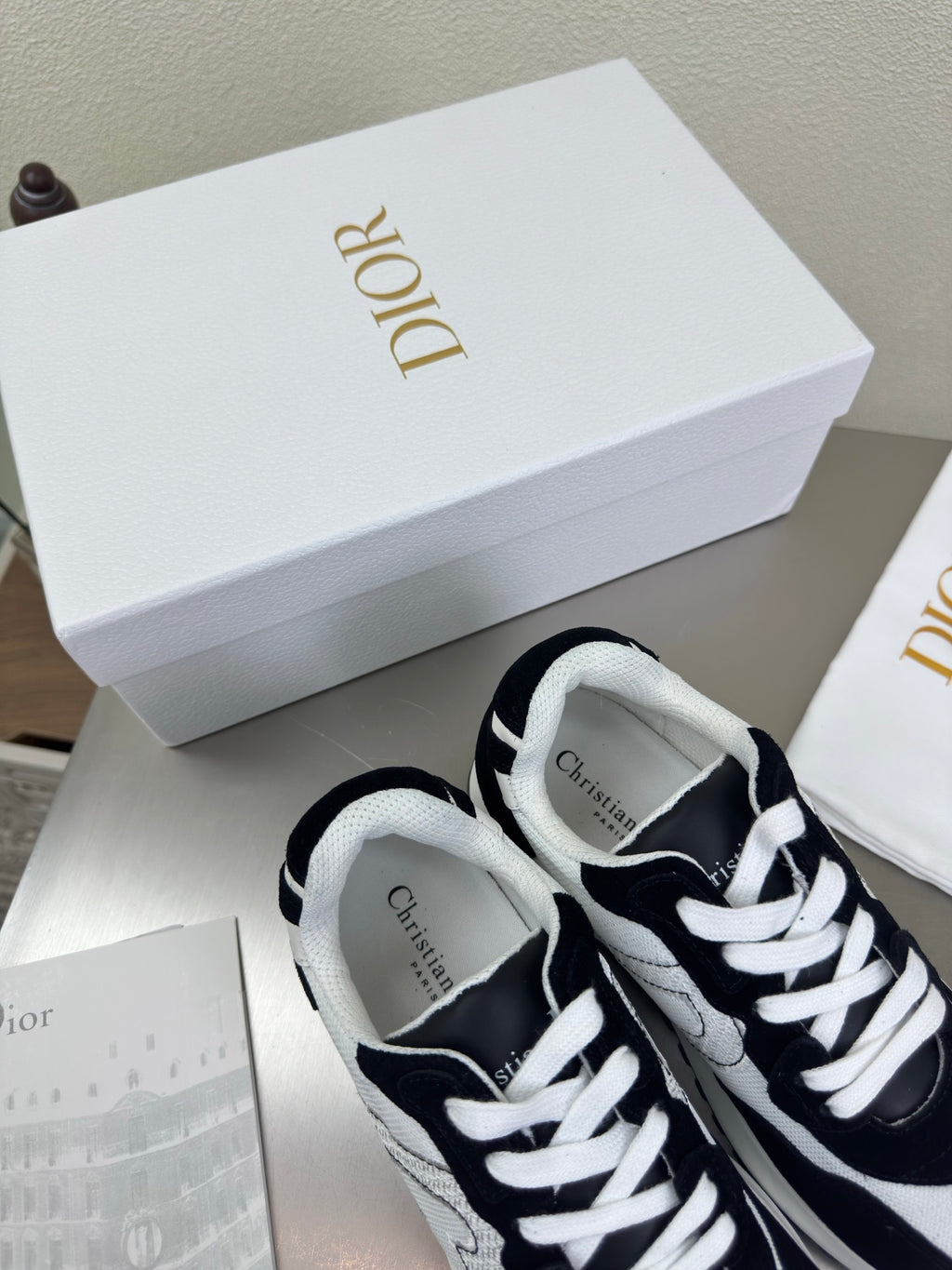 Black and white lace-up sneakers with white laces and Dior logo on the tongue
