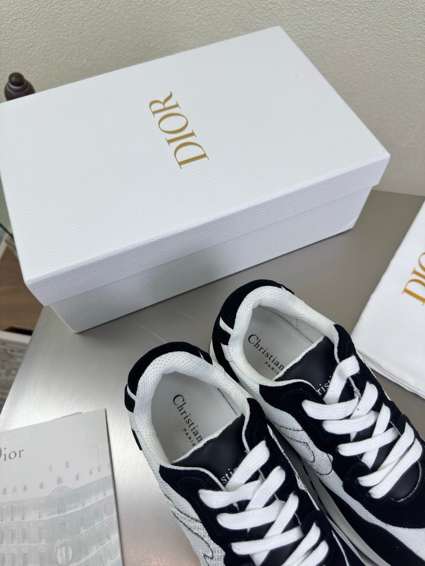 Black and white lace-up sneakers with white laces and Dior logo on the tongue