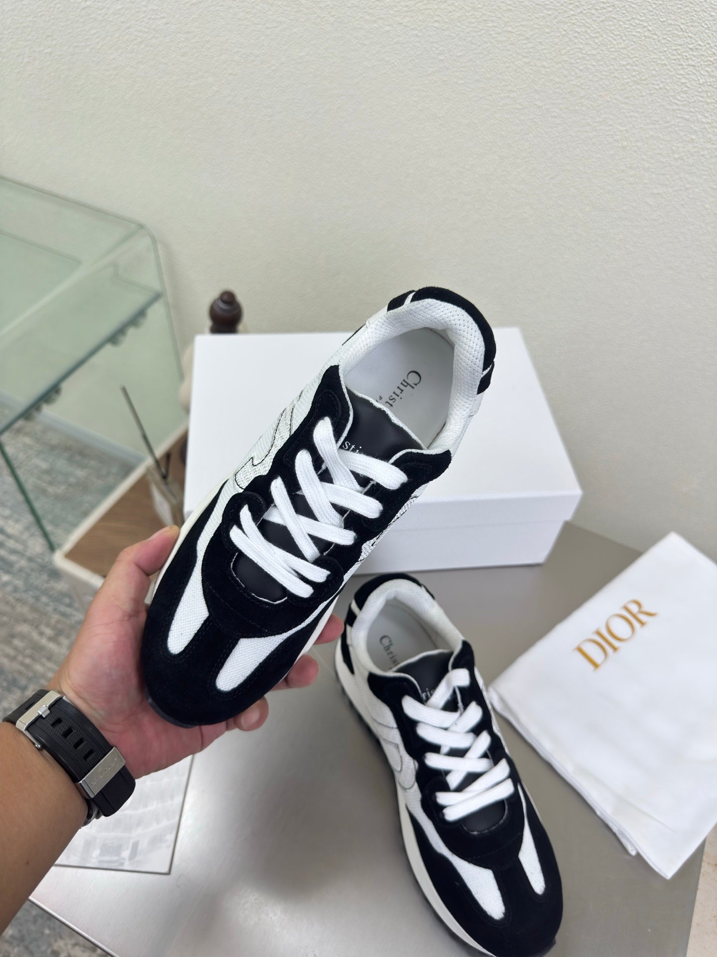Black and white lace-up sneakers with white laces and ribbed outsole, held close