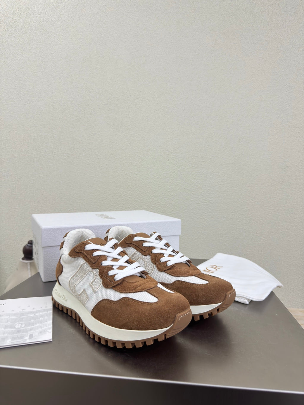Brown and white sneakers with white laces on display table, pair front view