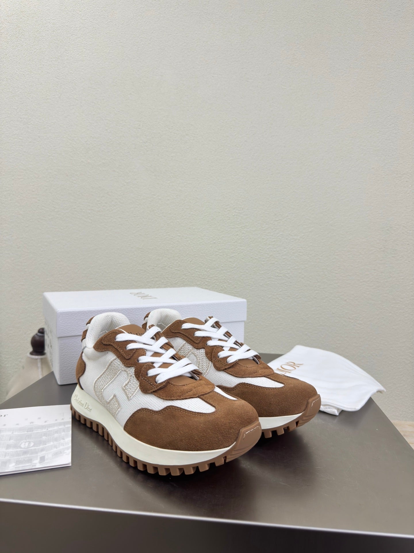 Brown and white sneakers with white laces on display table, pair front view