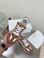 Brown and white sneakers held in hand, white laces and padded white interior