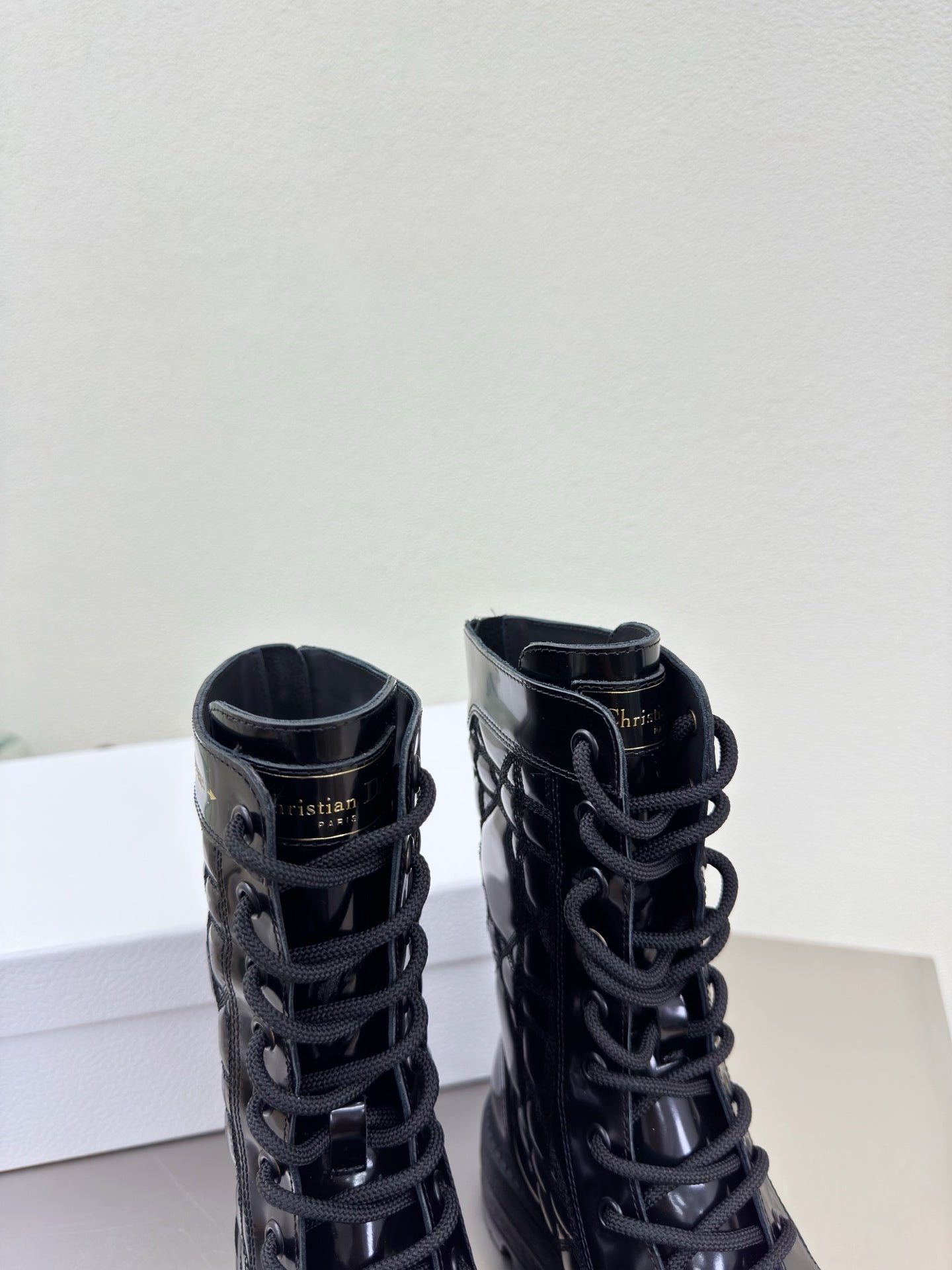 Black lace-up combat boots with padded collars and glossy finish