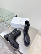 Pair of black mid-calf boots with buckles and chunky treaded outsole