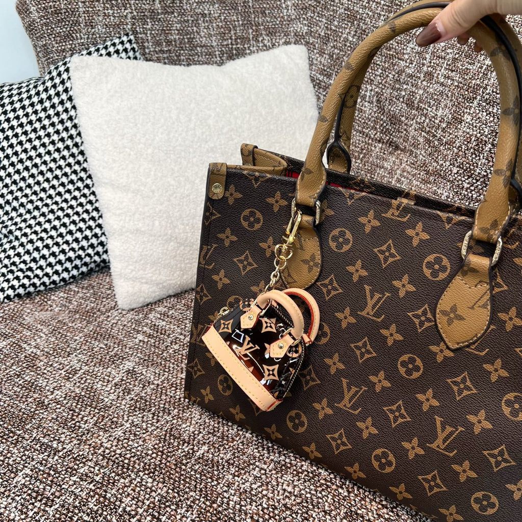 Louis Vuitton monogram handbag with tan handle, keyring charm, and zipper top