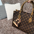 Louis Vuitton monogram handbag with tan handle, keyring charm, and zipper top