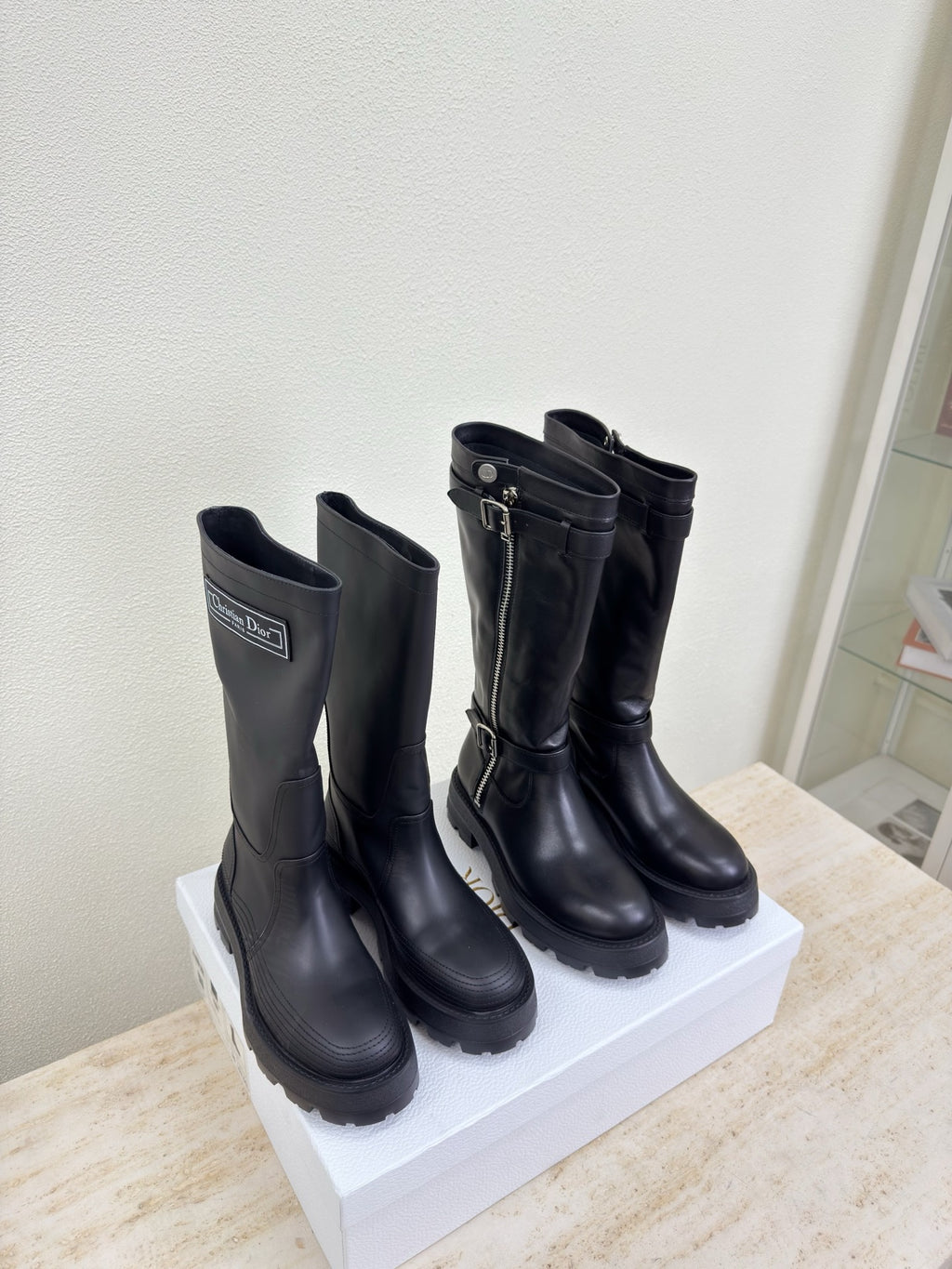 Black knee-high boots on display with buckles and side zippers, pair view