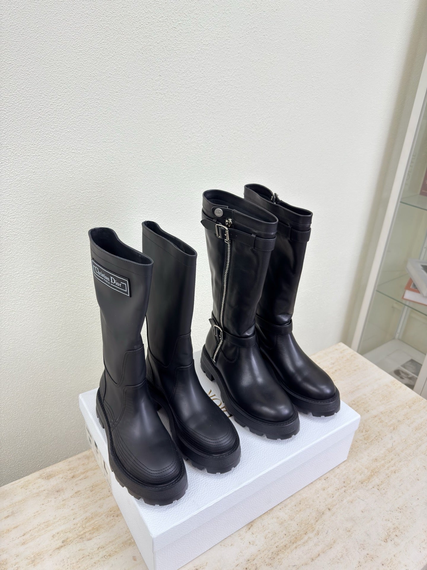Black knee-high boots on display with buckles and side zippers, pair view