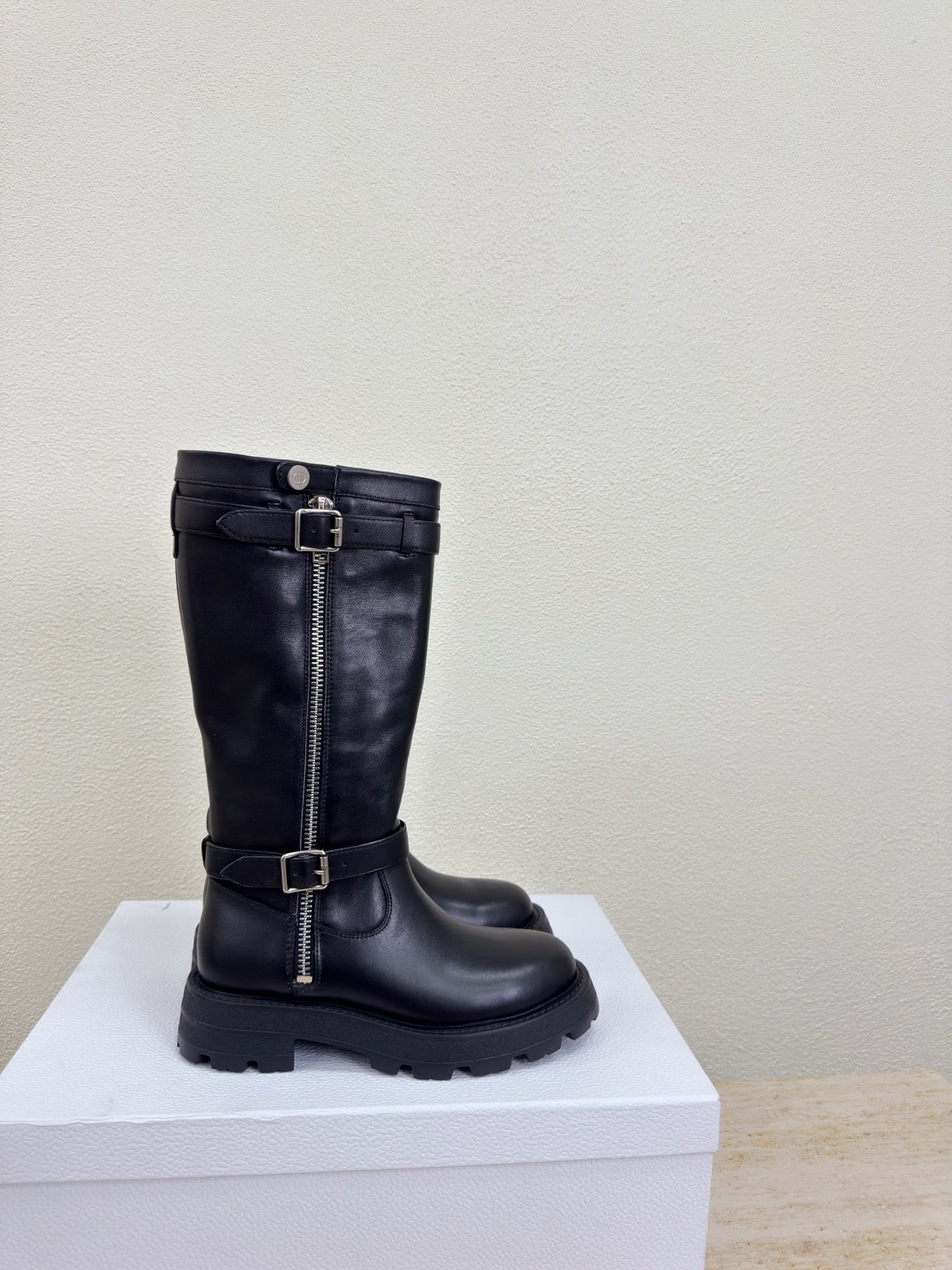 Black knee-high boot with side zipper and buckle strap, side view