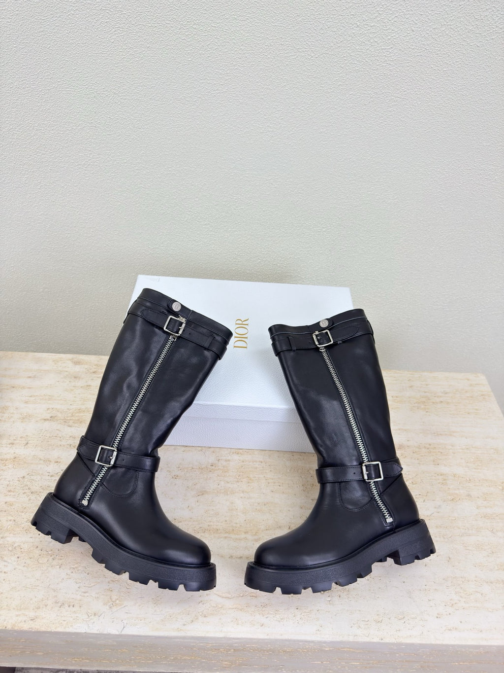 Pair of black knee-high boots with buckle straps and side zippers, front view