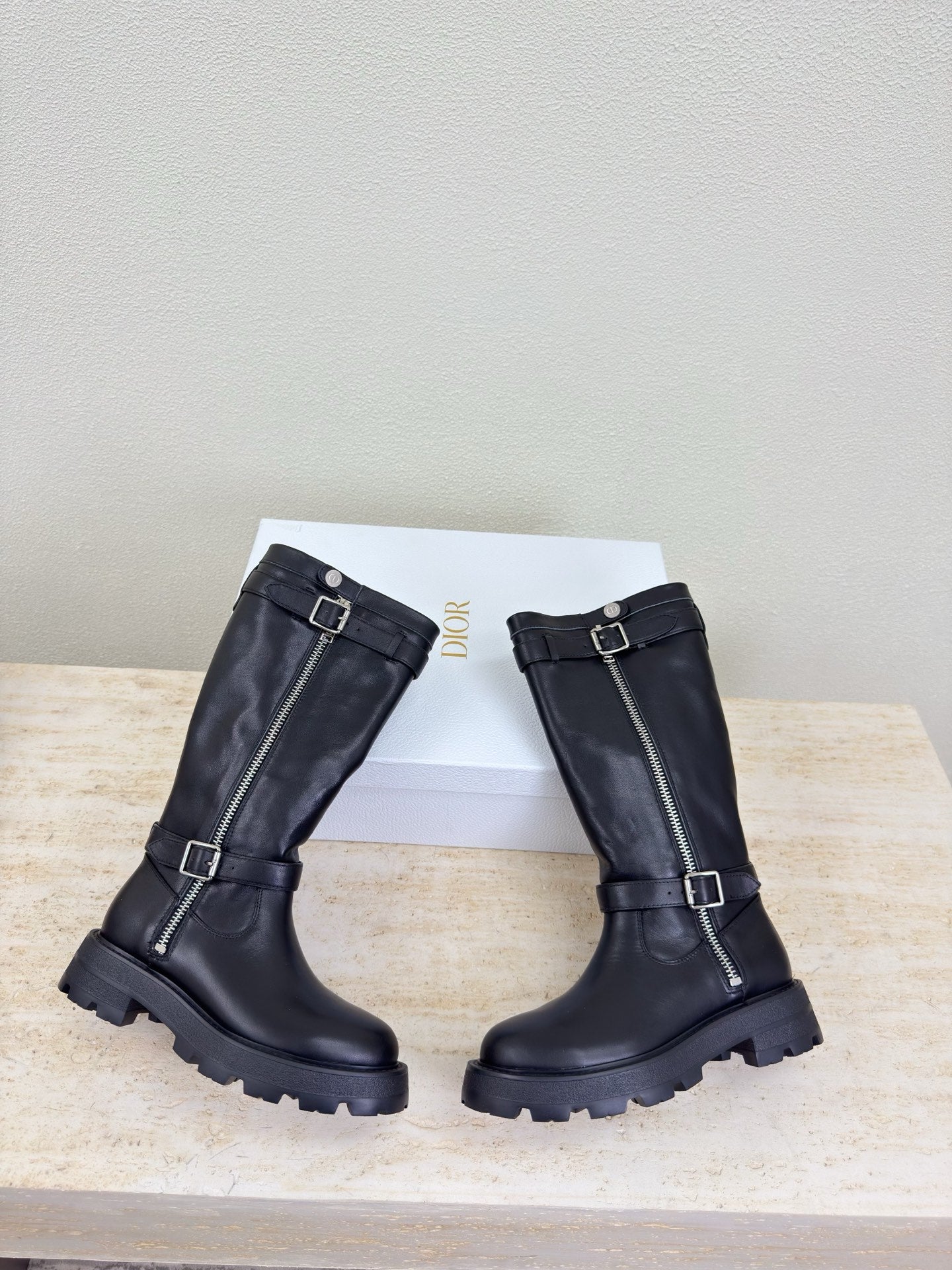 Pair of black knee-high boots with buckle straps and side zippers, front view