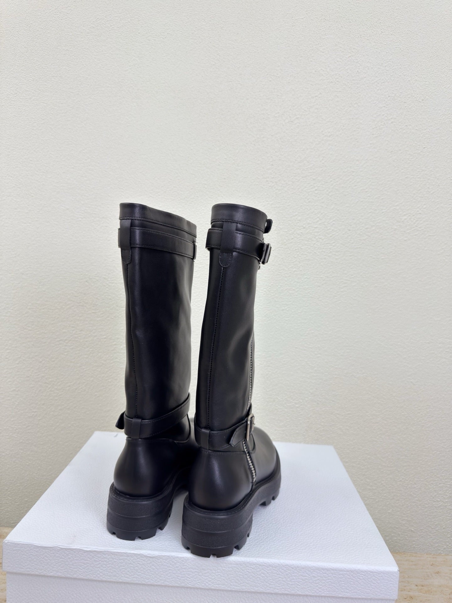 Black knee-high boots showing back panels and chunky lug heels, pair view