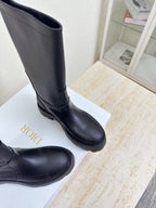 Women's dark knee-high boot close-up with stitched toe and lug sole