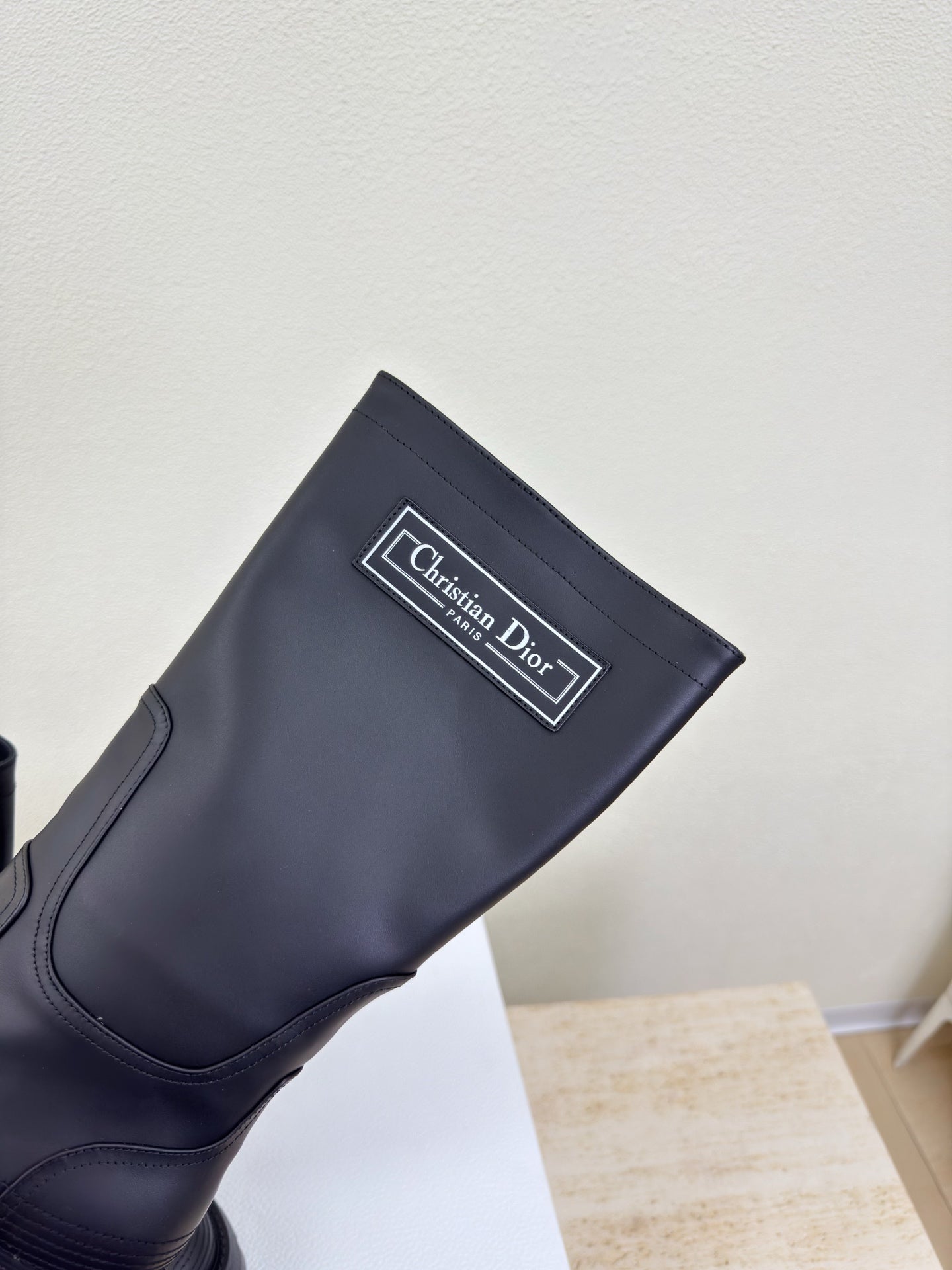 Women's dark knee-high boot with Christian Dior logo patch near ankle