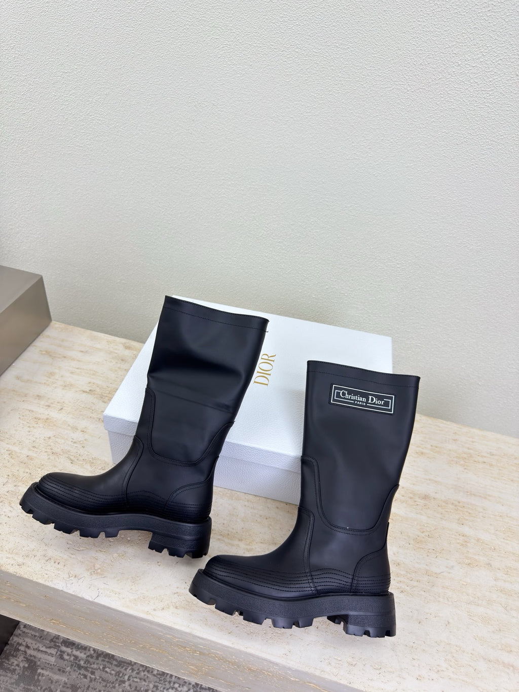 Women's dark knee-high boots, pair side-by-side on display platform