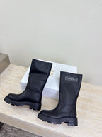 Women's dark knee-high boots, pair side-by-side on display platform