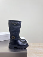 Women's black quilted mid-calf boots with buckle belt and thick tread sole