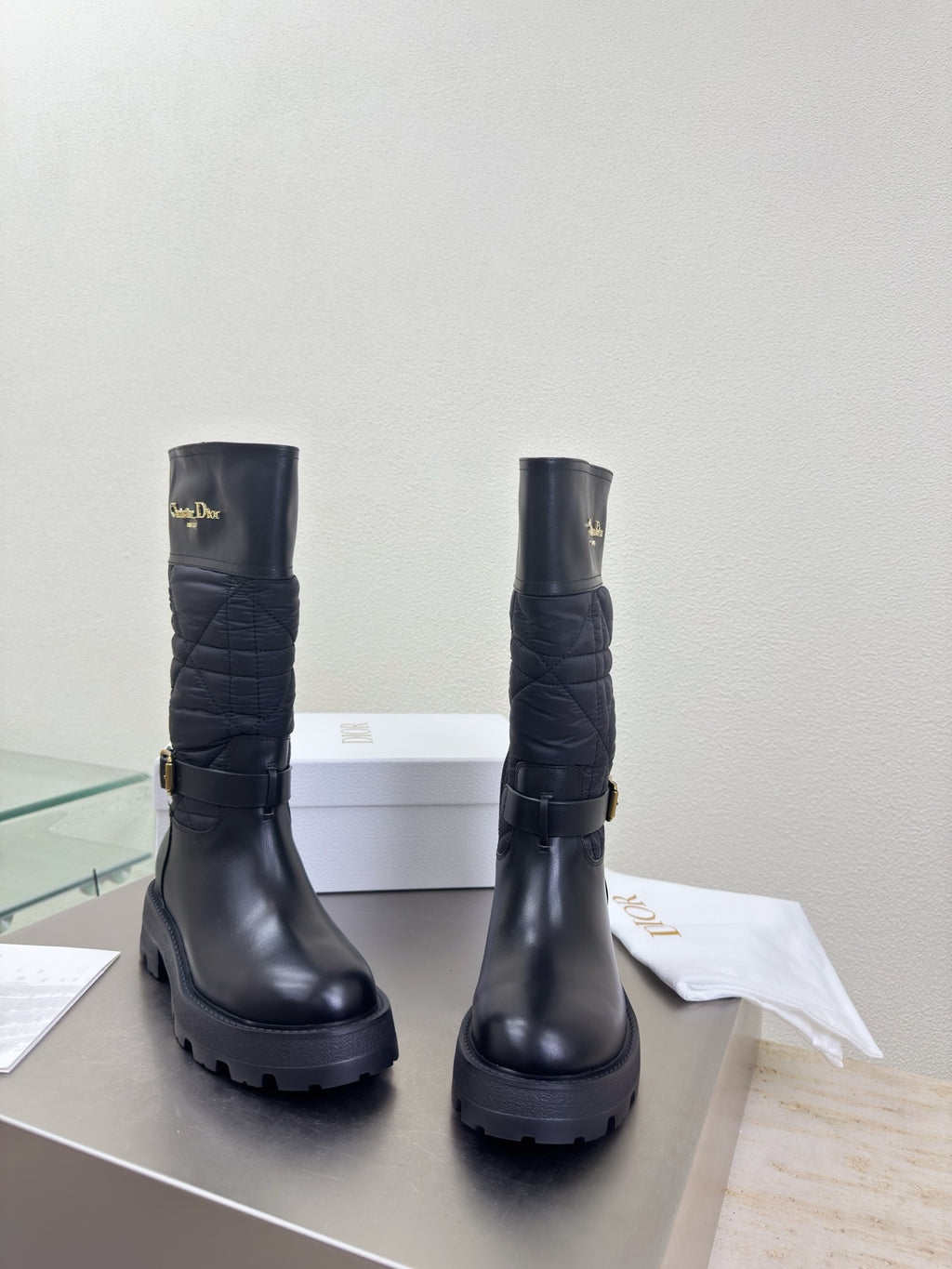 Women's black quilted mid-calf boots with buckle straps and chunky tread soles