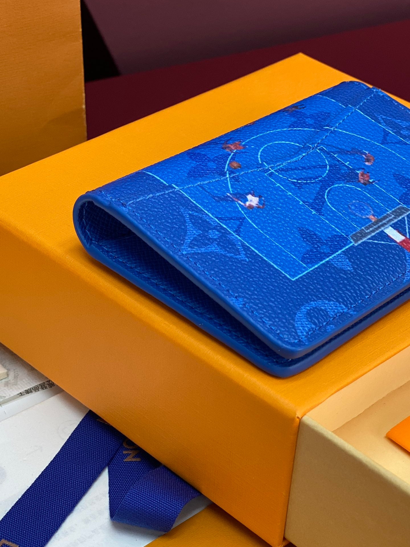 Blue small bag rolled on its side, featuring a printed motif on the flap