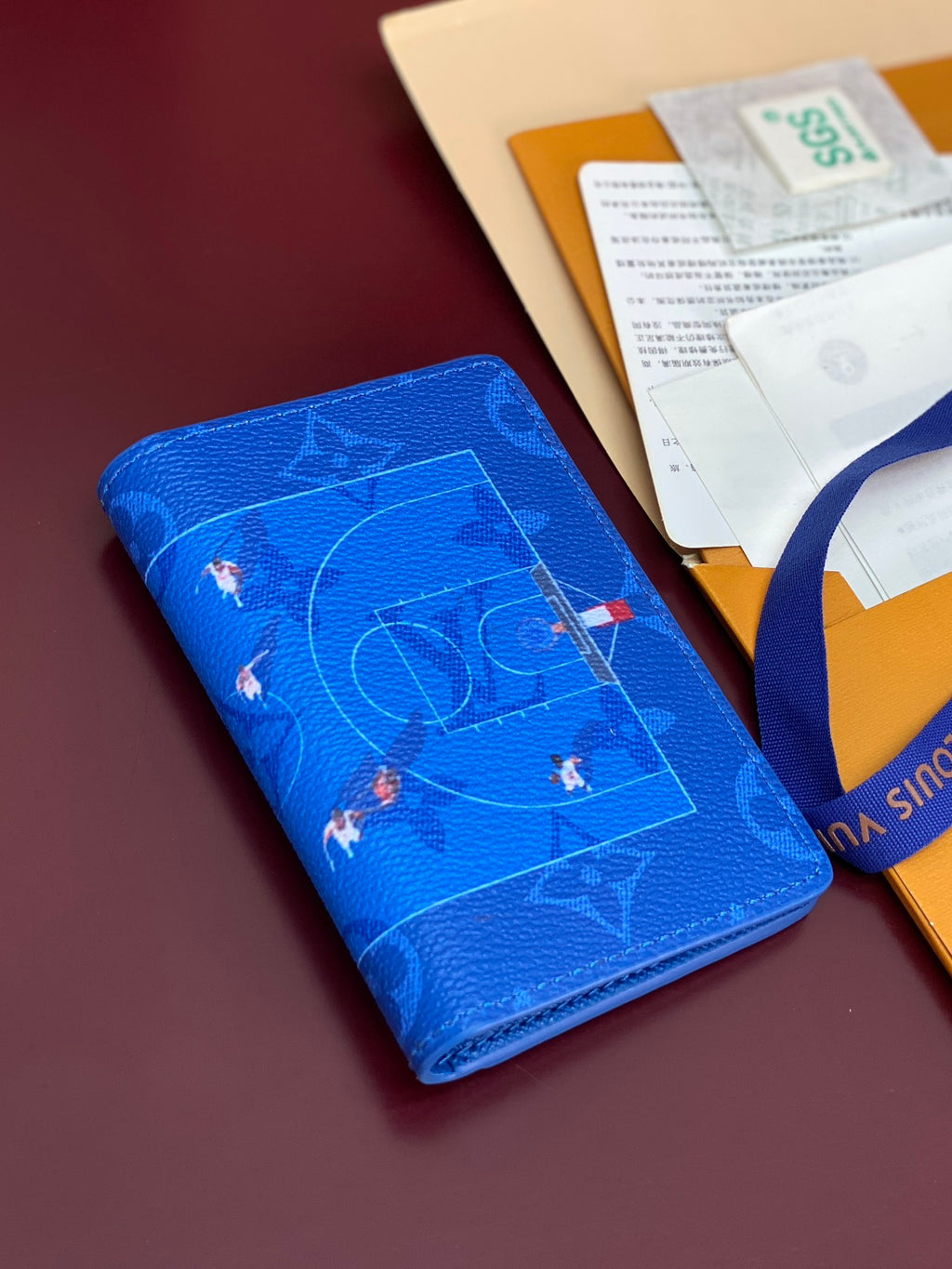 Blue small bag with all-over printed motif, displayed near a package insert