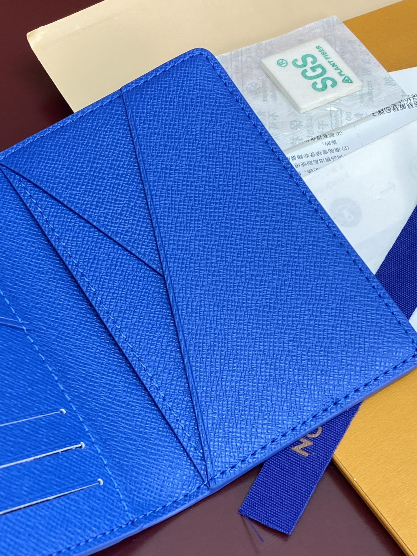 Blue small bag close-up of flap folds and stitched leather texture