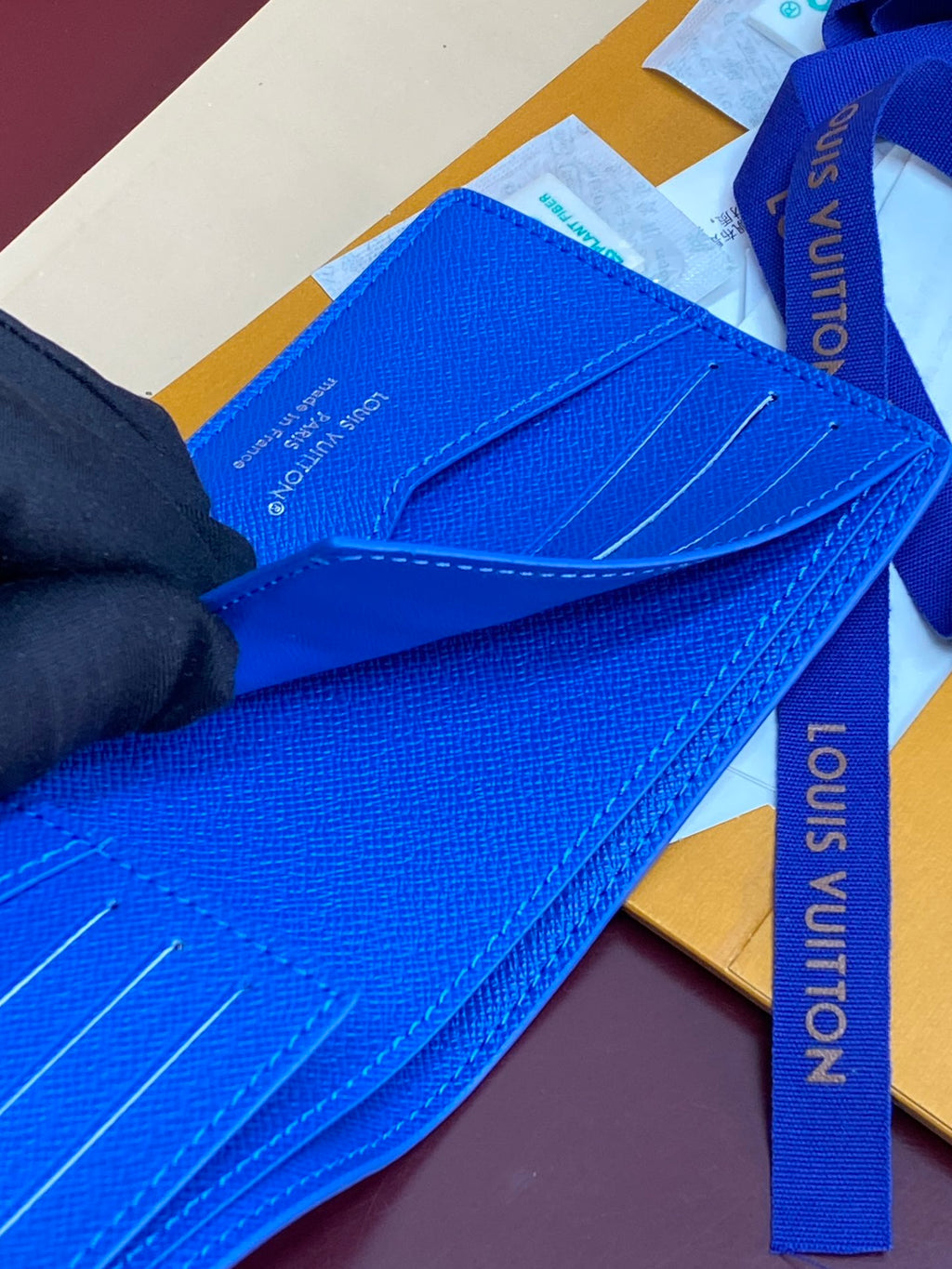 Blue Louis Vuitton small wallet close-up with stitched card pocket and strap